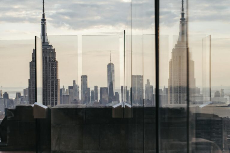Through fenced rooftop view of skyscraper facade under cloudy sky in New York City